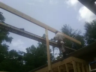 Carpenter setting a ridge beam over a new addition frame — Ice Dam Removal by Roofing Brothers in Mesick