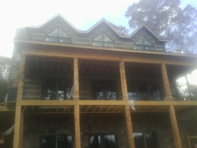 Dormers and porch framing on a large log home under construction — Roof Coating work by our crew in Mesick