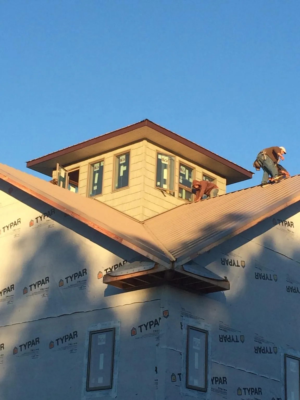 Roofers working around a rooftop cupola on a new metal roof at sunset — Roof Waterproofing in Mesick by Roofing Brothers